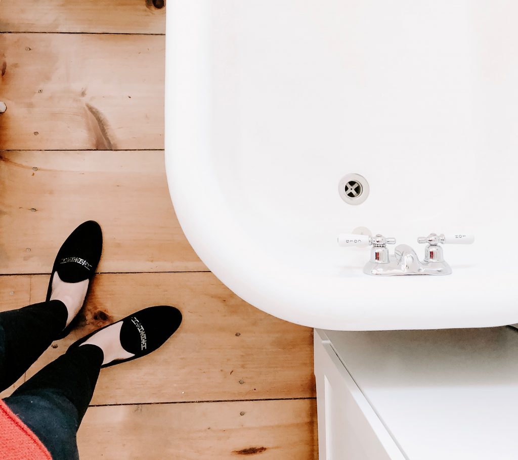 Clawfoot tub with wide plank floors and black loafers
