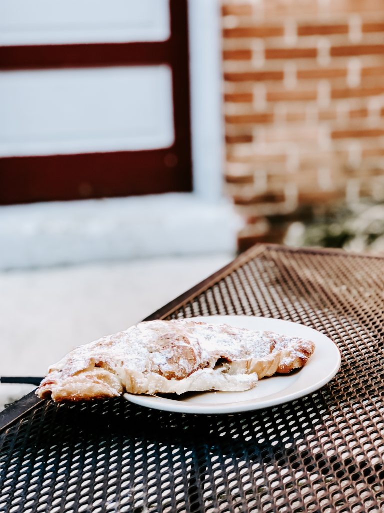 Iron table with large croissant in front of a brick wall